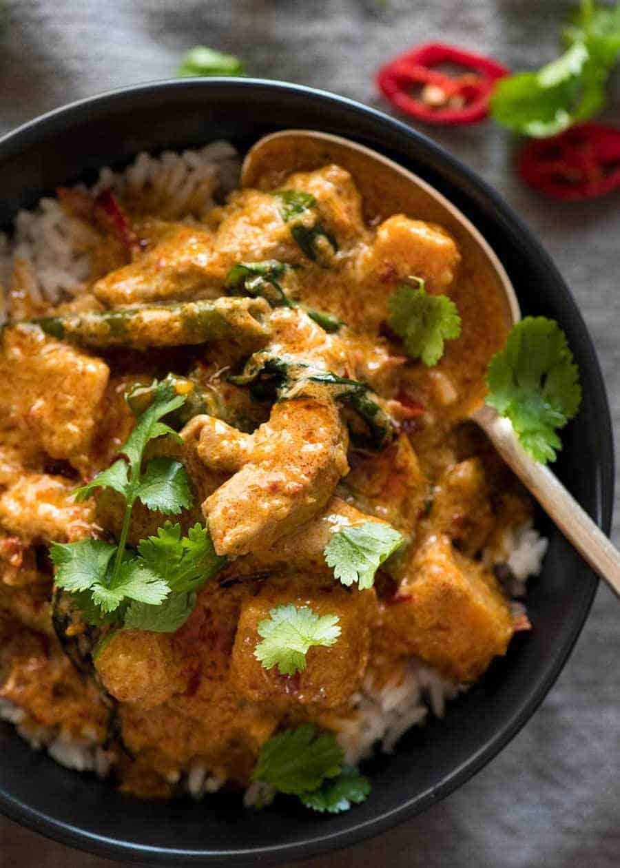 Thai Red Curry with Chicken served over rice, in a black rustic bowl, ready to be served.