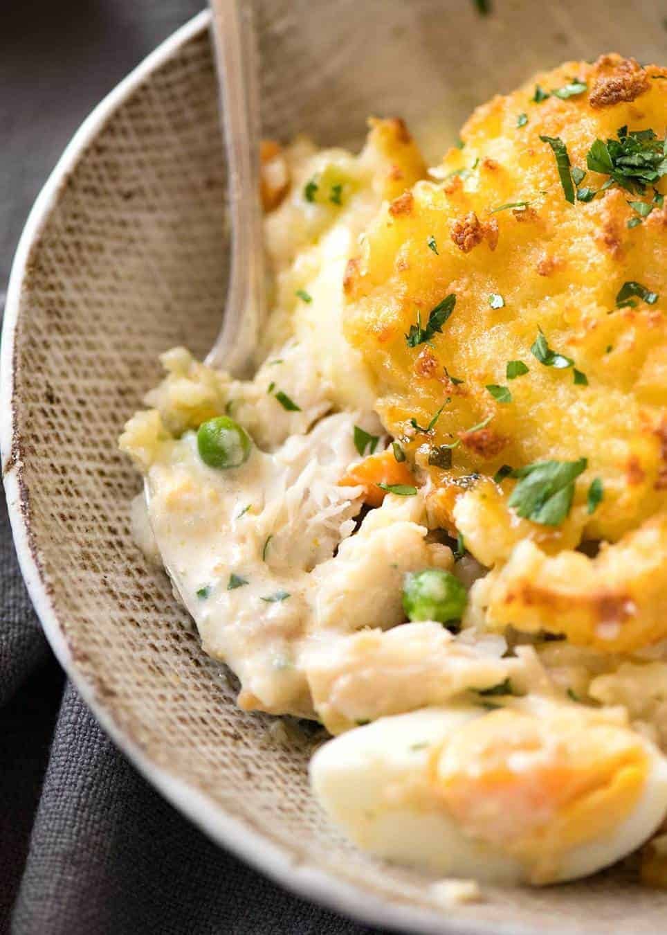 Close up of Fish Pie in rustic brown serving bowl with fork