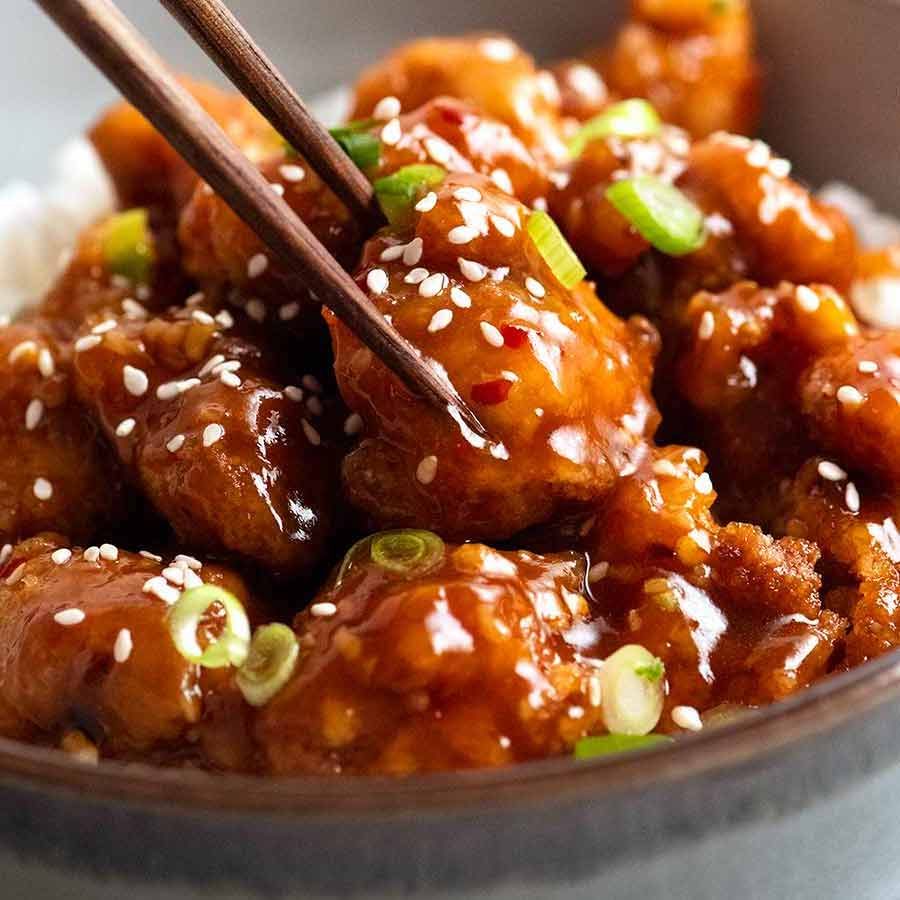 Close up of chopsticks picking up a piece of General Tso's Chicken